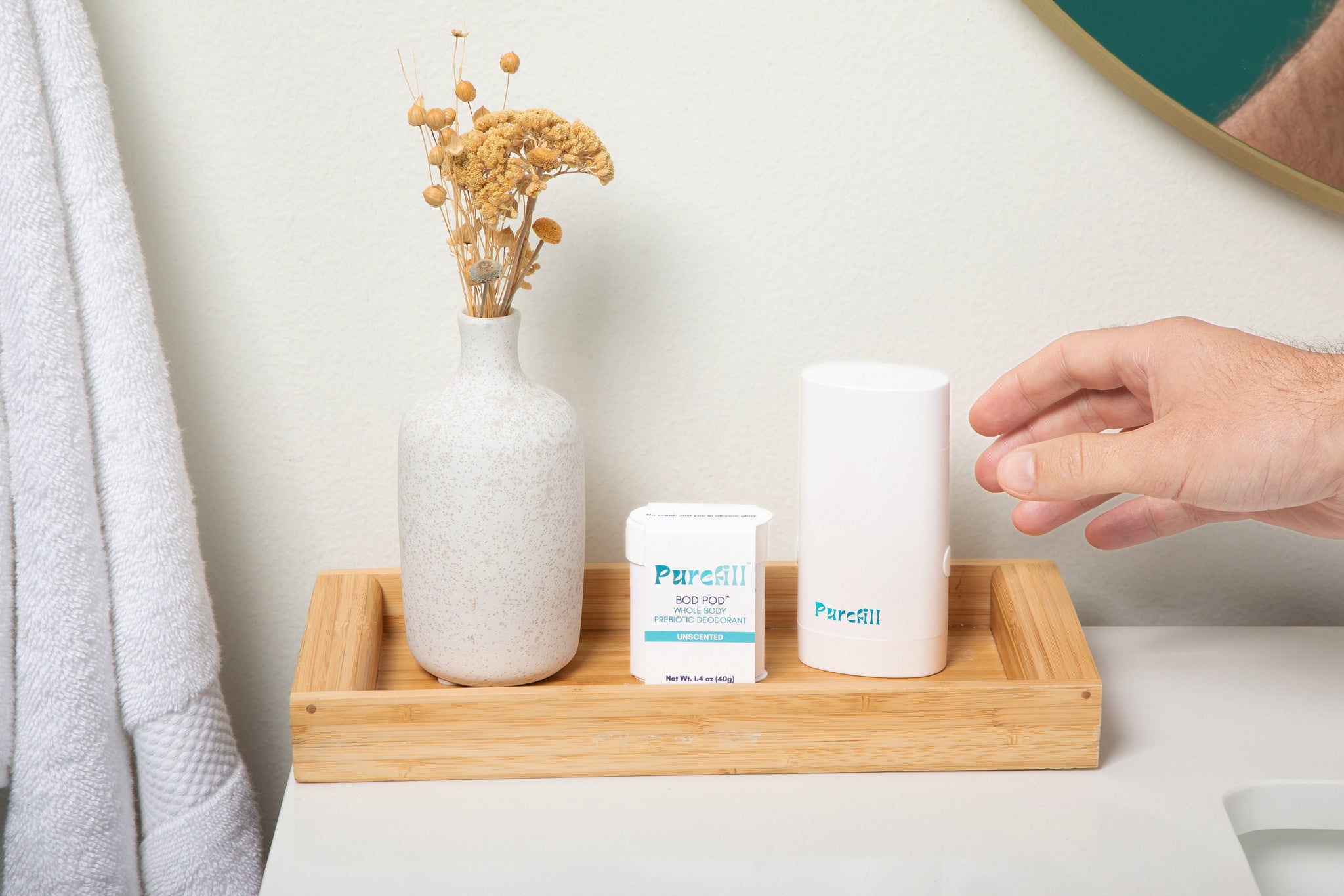 Purefill White Opal Refillable Case with Unscented Bod Pod  Sat In a Bathroom Wooden Tray with A White Vase.