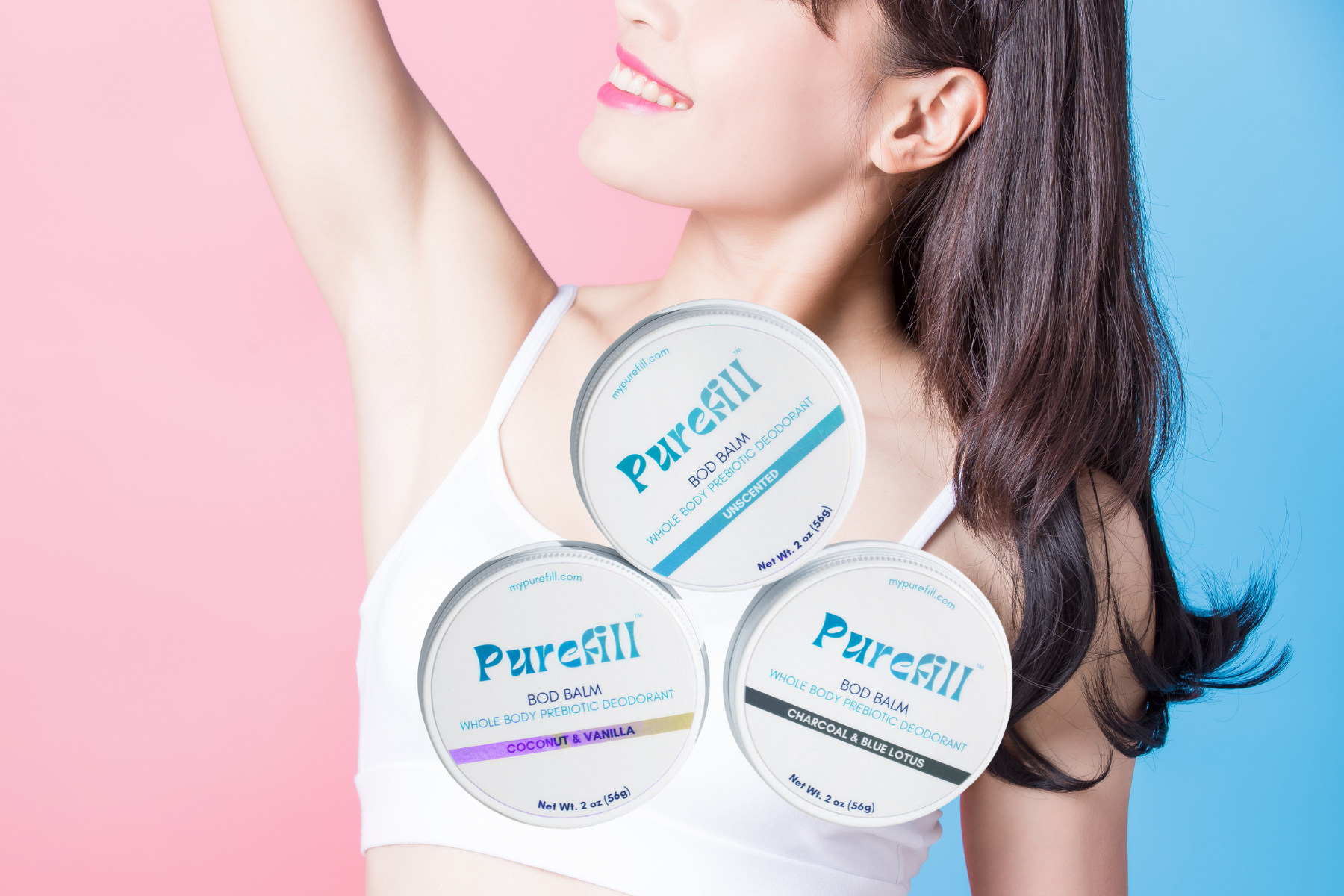 Pink and blue background with woman in background with a crop top on arms in the air with a 3 pack bod balm in front of her